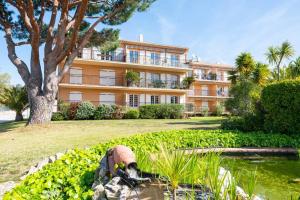 duży pomarańczowy budynek z drzewem i stawem w obiekcie Les Jardins de Provence • Beau Rivage • Proche mer w mieście Carqueiranne