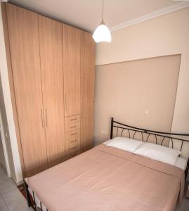 1 dormitorio con 1 cama y armario de madera en SAVVAS en Néa Pláyia