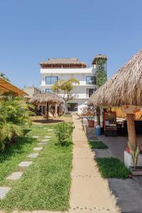 a pathway leading to a building with thatched roofs at SurfNest Hostel in Brisas de Zicatela