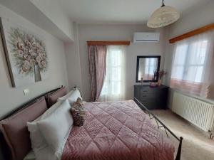 a bedroom with a bed and a dresser and windows at Anemone Rose - Chora center in Andros