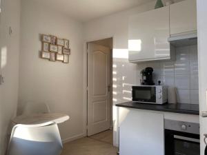 une cuisine blanche avec un micro-ondes et un tabouret à l'intérieur dans l'établissement Appartement à découvrir, à Marquette-lès-Lille