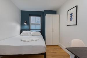 a bedroom with a white bed and a blue wall at West Broadway Quarters by Thatch in Boston