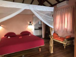 a bedroom with a red bed with a canopy at Villa Mbolatsara in Nosy Be