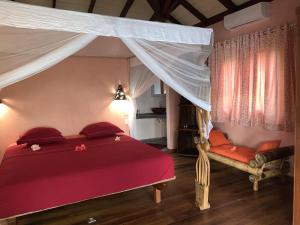 1 dormitorio con cama roja y dosel en Villa Mbolatsara, en Nosy Be