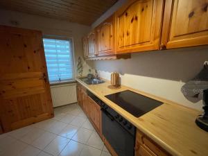 cocina con armarios de madera, fregadero y fogones en Haus Rubi en Cochem