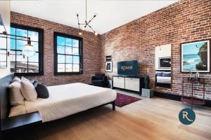 Un dormitorio con una pared de ladrillo y una cama grande en Roami at The Lola, en Nueva Orleans