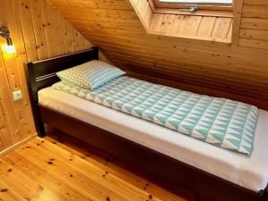 a small bed in a room with a wooden floor at Domki Wczasowe Papaya in Kołobrzeg