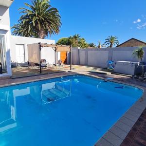 einen Pool im Hinterhof mit einem Zaun und Palmen in der Unterkunft 51 On Vlei in Kapstadt