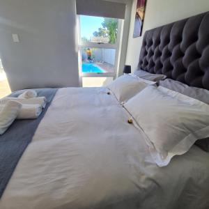 uma cama com almofadas brancas, uma cabeceira e uma janela em 51 On Vlei em Cidade do Cabo