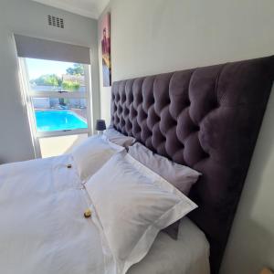 Schlafzimmer mit einem Bett mit einem großen gepolsterten Kopfteil in der Unterkunft 51 On Vlei in Kapstadt