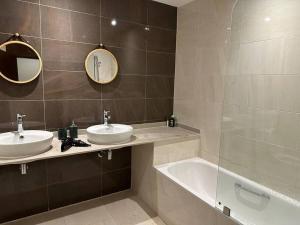 une salle de bain avec deux lavabos, une baignoire et un miroir dans l'établissement Luxury Apartment Hilton 5*, à Tanger 17 autres photos