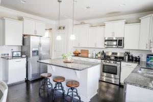 a kitchen with white cabinets and a counter with stools at Charming 5 Bedroom spacious Home (sleeps 12-14) in Piedmont