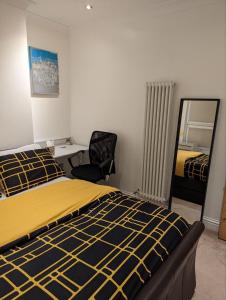 1 dormitorio con cama, silla y espejo en Fully-equipped flat in the city of London. en Londres