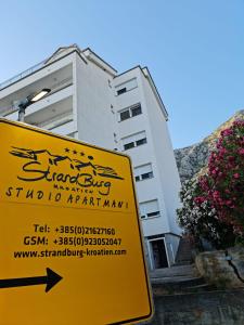 a yellow sign in front of a building at Apartments Strandburg Kroatien in Živogošće