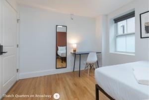 a bedroom with a bed and a table and a mirror at West Broadway Quarters by Thatch in Boston
