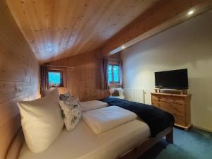 a bedroom with a bed and a television in a room at Bergmomente Montafon Ferienhaus Bitschweil in Tschagguns