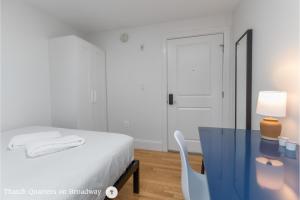 a bedroom with a white bed and a blue table and chair at West Broadway Quarters by Thatch in Boston