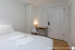 a bedroom with a white bed with a desk and a door at West Broadway Quarters by Thatch in Boston