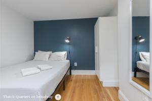 a bedroom with a white bed and a blue wall at West Broadway Quarters by Thatch in Boston