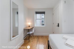 a bedroom with a bed and a desk and a window at West Broadway Quarters by Thatch in Boston