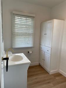 uma casa de banho branca com um lavatório e um frigorífico em Dwell Seaview em Seaview