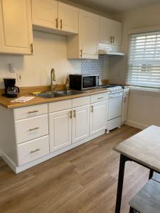 uma cozinha com armários brancos, um lavatório e um micro-ondas em Dwell Seaview em Seaview