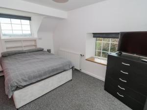 a bedroom with a bed and a flat screen tv at Rhous in Llanallgo