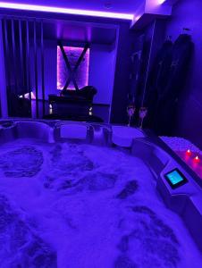 a room with a tub with purple lighting and a piano at Loveroom Metz Spa Privatif in Metz