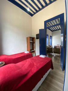 a bedroom with two red beds and a living room at Pousada Usina Paraíso in Astolfo Dutra