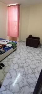 a bedroom with a marble floor with a bed and a chair at Wummies place in Abu Dhabi