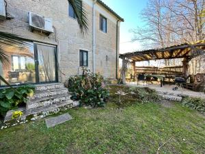 a stone house with a garden and a patio at A comfortable rural space in beautiful gardens in Oliveira do Hospital