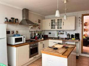 a kitchen with white cabinets and a counter with a microwave at A comfortable rural space in beautiful gardens in Oliveira do Hospital