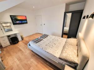 um quarto com uma cama e uma televisão na parede em LMK, 2 Bedroom Apartment, with Roof Terrace, Free parking, EV Charger, Great Location. em Belfast