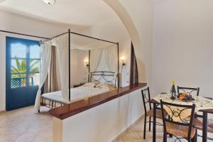 a bedroom with a canopy bed and a dining table at Sea Melody in Lefkos Karpathou