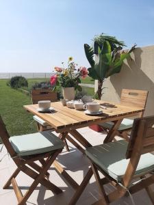 einen Picknicktisch aus Holz mit Stühlen und Blumen auf einer Terrasse in der Unterkunft Studio-terrasse 3* bord de mer Châtelaillon plage in Châtelaillon-Plage