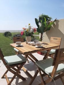 - une table de pique-nique en bois avec des chaises et des fleurs sur la terrasse dans l'établissement Studio-terrasse 3* bord de mer Châtelaillon plage, à Châtelaillon-Plage