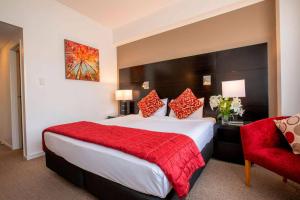 a hotel room with a large bed with a red blanket at Mercure Wellington Abel Tasman Hotel in Wellington