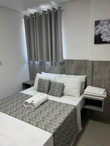 1 dormitorio con 1 cama grande con sábanas y almohadas blancas en Apartamento com piscina no Condominio Maraca2 en Ipojuca