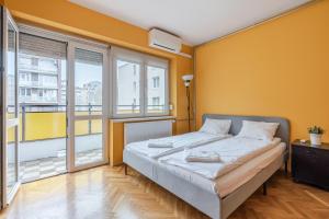 ブダペストにあるBpR Castle Point Apartmentのベッドルーム1室(黄色い壁と窓のあるベッド1台付)