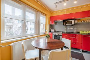 ブダペストにあるBpR Castle Point Apartmentのキッチン(赤いキャビネット、木製テーブル、椅子付)