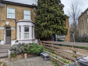 una casa con una recinzione e una panchina di fronte ad essa di Fully-equipped flat in the city of London a Londra