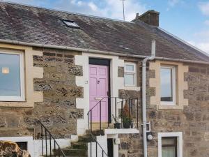 ein Backsteinhaus mit einer rosa Tür in der Unterkunft Cromwell Cottage in Burntisland