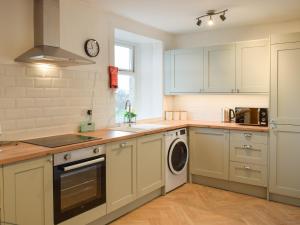 a kitchen with white cabinets and a sink and a dishwasher at Cromwell Cottage in Burntisland