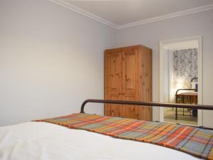 a bedroom with a bed and a wooden cabinet at Cromwell Cottage in Burntisland