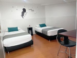 a room with two beds and a table and a desk at Casa Hotel Quinta Real in Bogotá