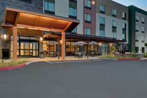 a building with tables and umbrellas in a parking lot at TownePlace Suites Sacramento Airport Natomas in Sacramento