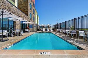 a swimming pool with tables and chairs next to a building at TownePlace Suites Sacramento Airport Natomas in Sacramento