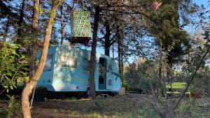 einem blauen Wohnwagen inmitten von Bäumen in der Unterkunft Ir por ai Arrábida in Azeitão