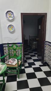 a room with a checkered floor with a chair and plates on the wall at Pensión San Benito Abad in Seville
