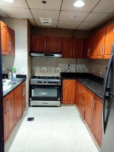 - une cuisine avec des placards en bois et une cuisinière dans l'établissement Walk to the Beach, Charming 3-Bedroom Home in Ajman Corniche Residences, à Ajman